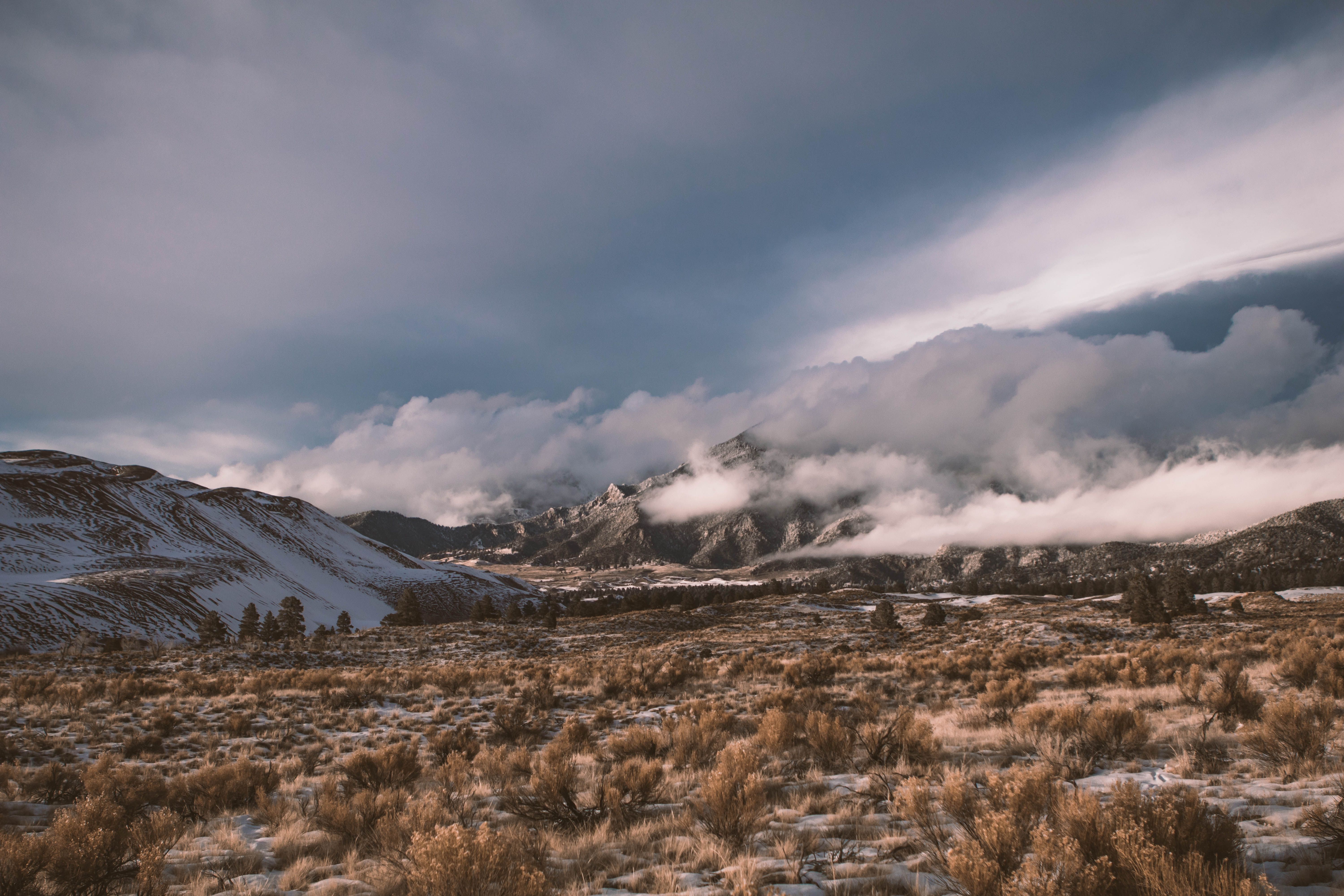 A landscape with clouds and snow in the distance · Free Stock Photo