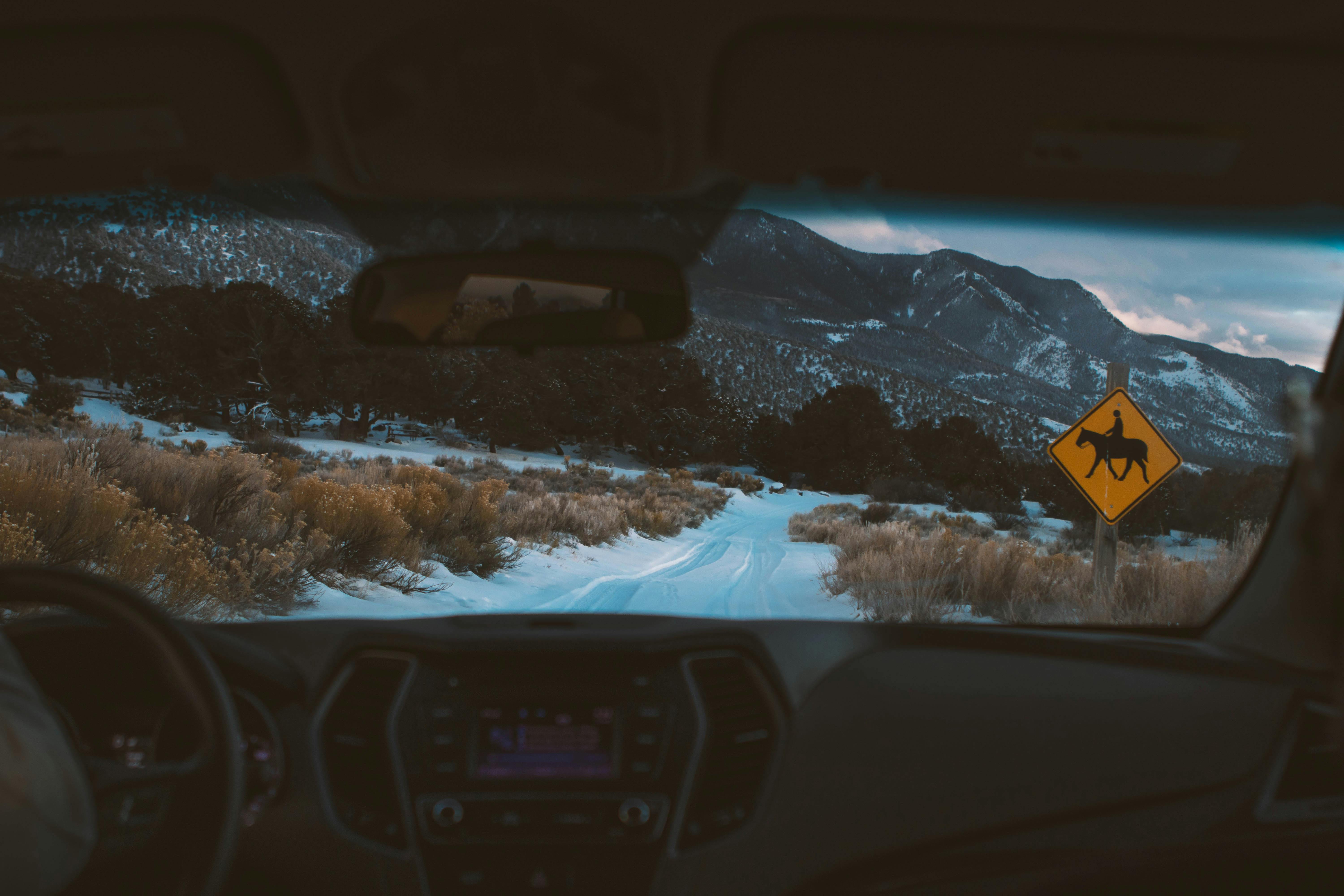 a car driving through a snowy road with a sign on the side