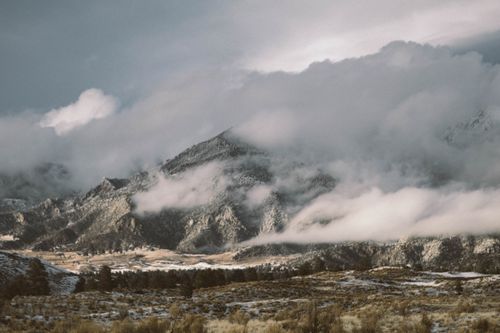Free Snow-covered mountains and misty clouds create a serene winter landscape perfect for travel and adventure enthusiasts. Stock Photo