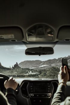 Driving through Garden of the Gods with a clear view of red rock formations and mountains.