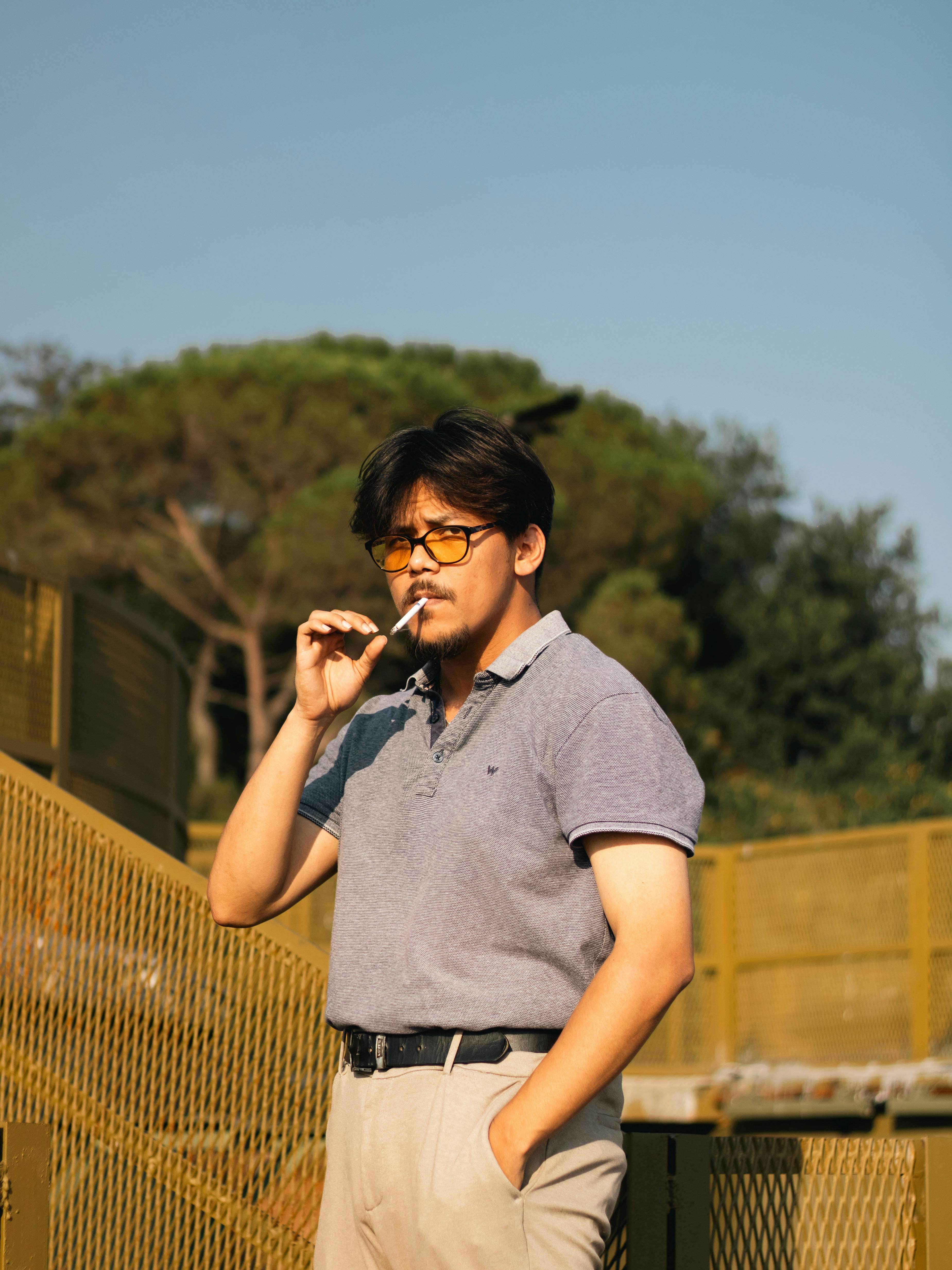 elegant fine looking man smoking a cigarette in a park