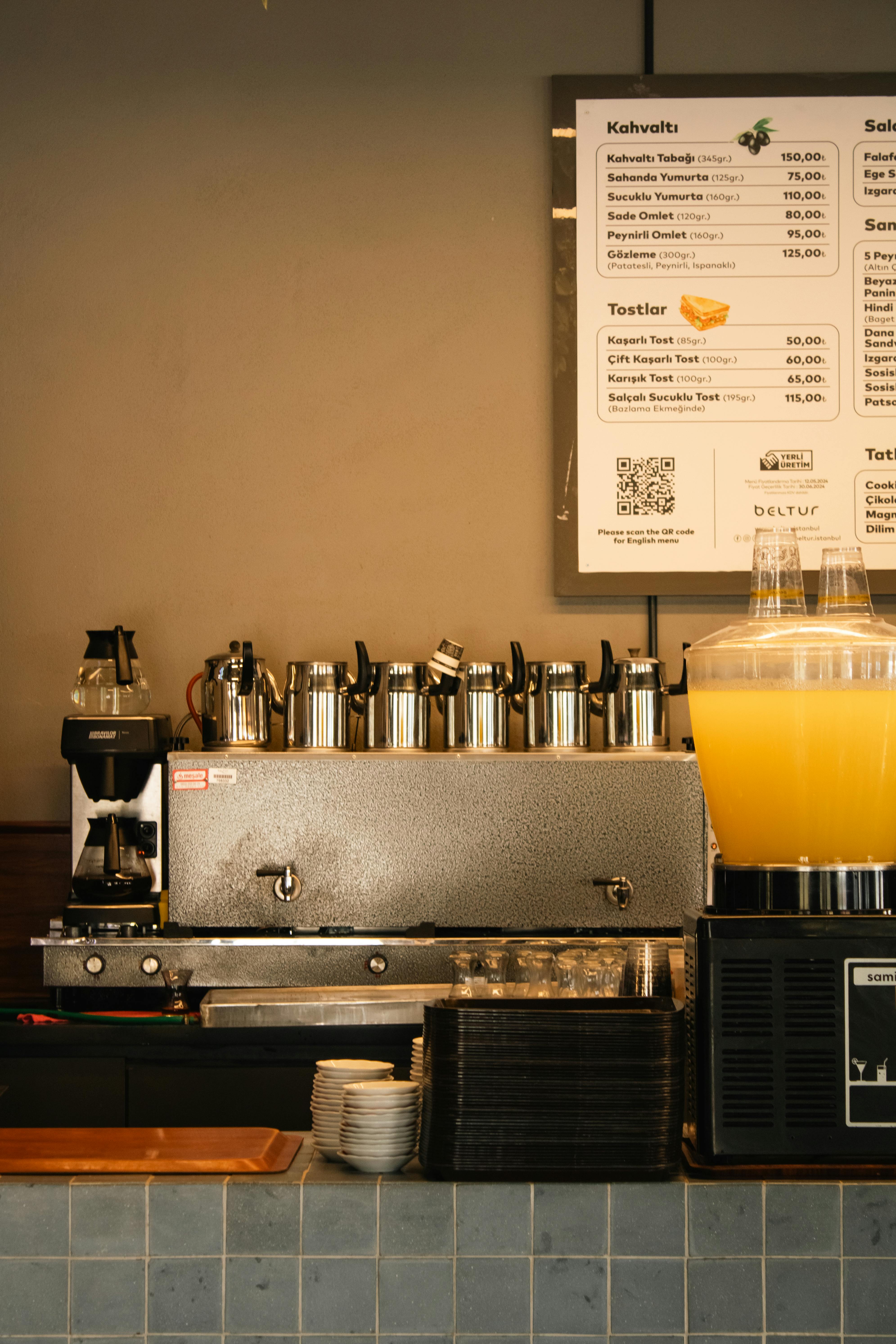 Cozy coffee shop counter featuring espresso machine and juice dispenser.