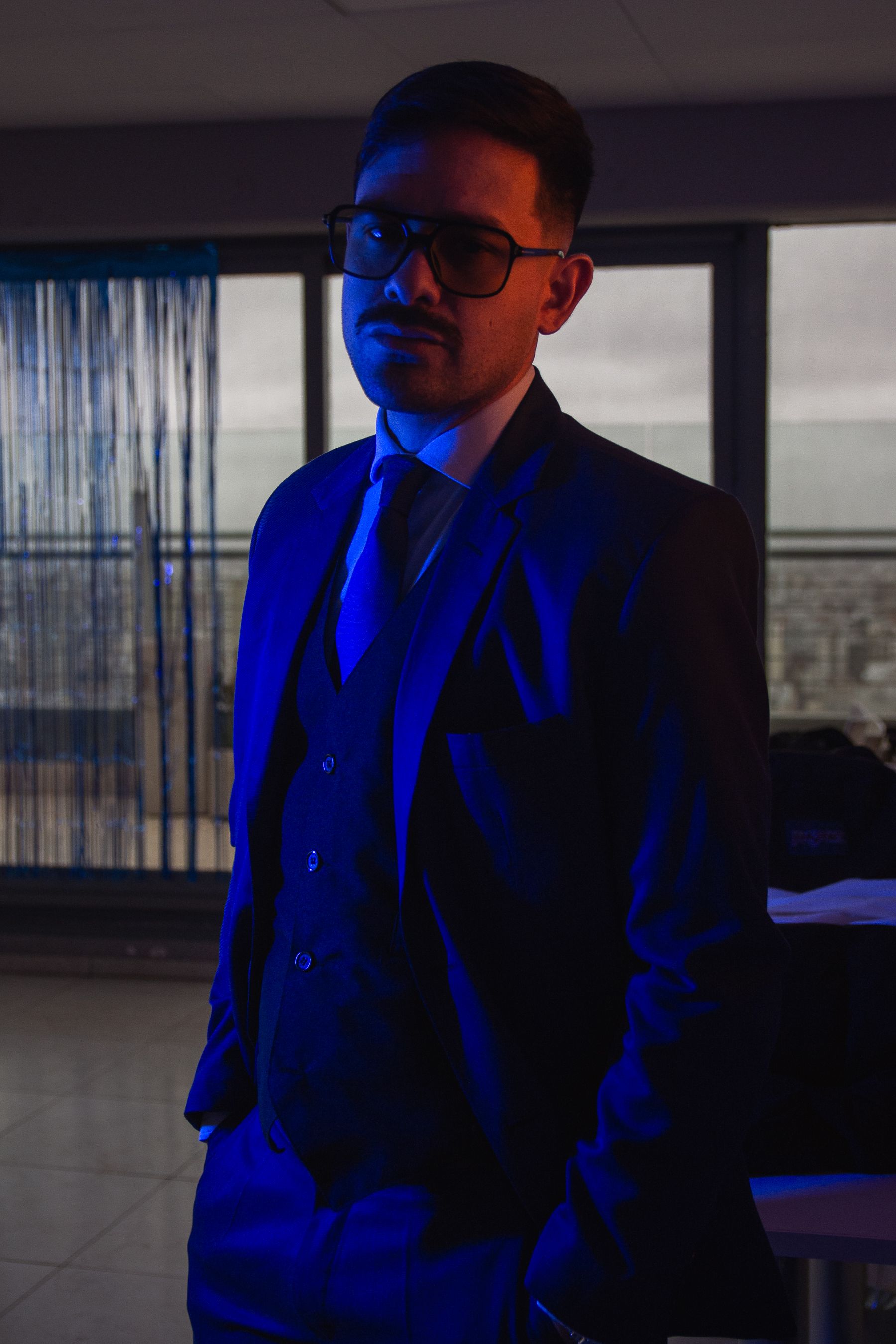 A man in a suit and tie standing in front of a window · Free Stock Photo