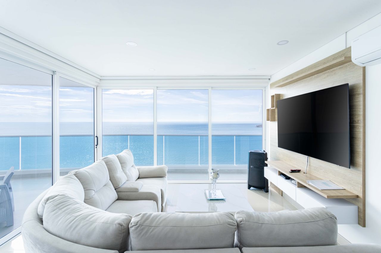 Bright white living room with curved sofa and floor-to-ceiling ocean views