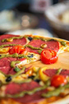 Delicious pepperoni pizza topped with fresh vegetables and pesto sauce.