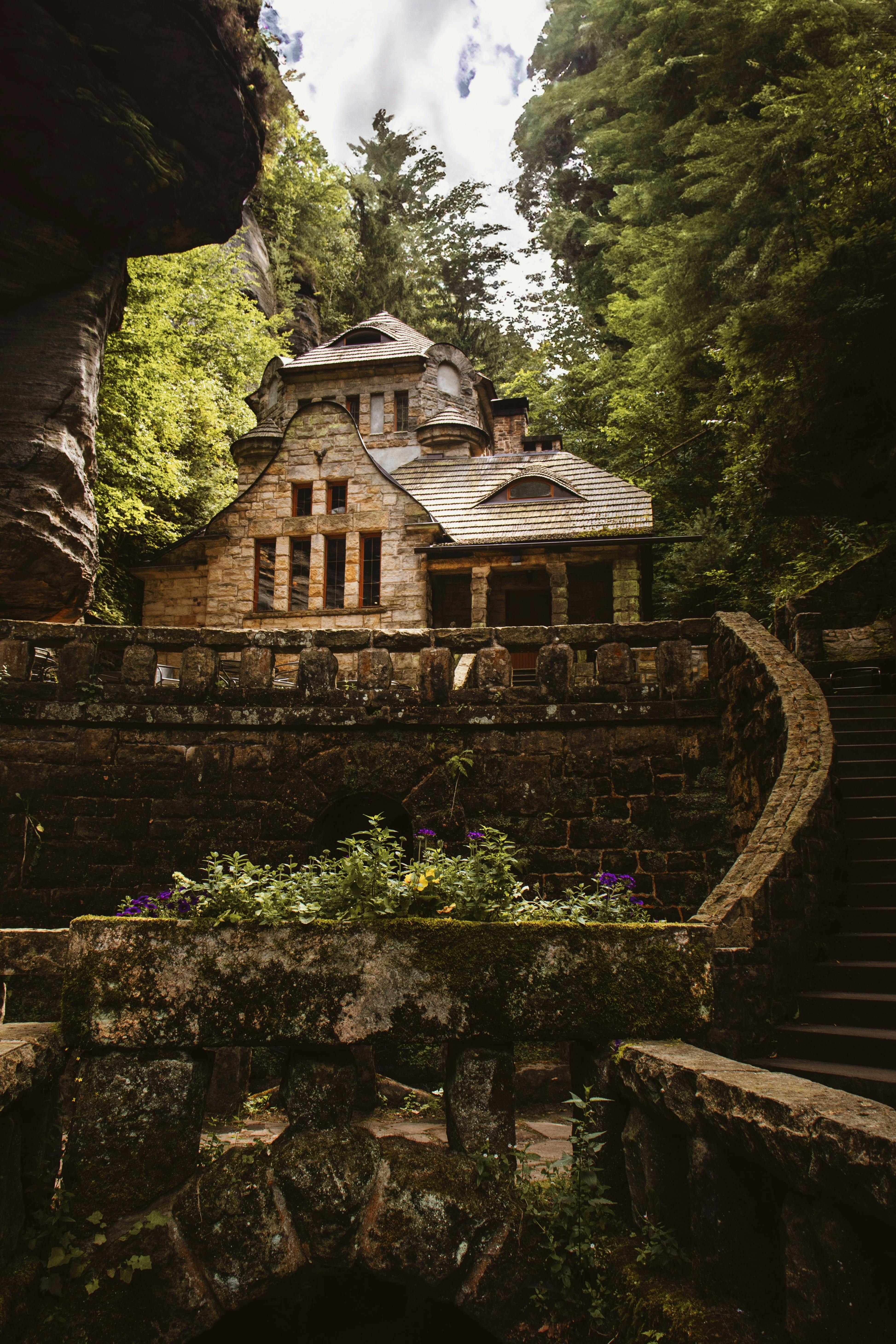 a stone house in the woods with stairs