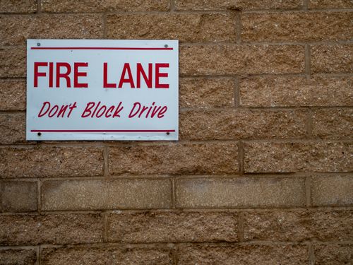 Free Close-up of a 'Fire Lane' warning sign on a textured brick wall. Stock Photo