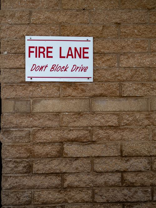 Free A fire lane sign on a beige brick wall indicating no parking allowed. Stock Photo
