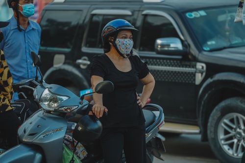 Free Woman with helmet and mask standing by a scooter in traffic Stock Photo