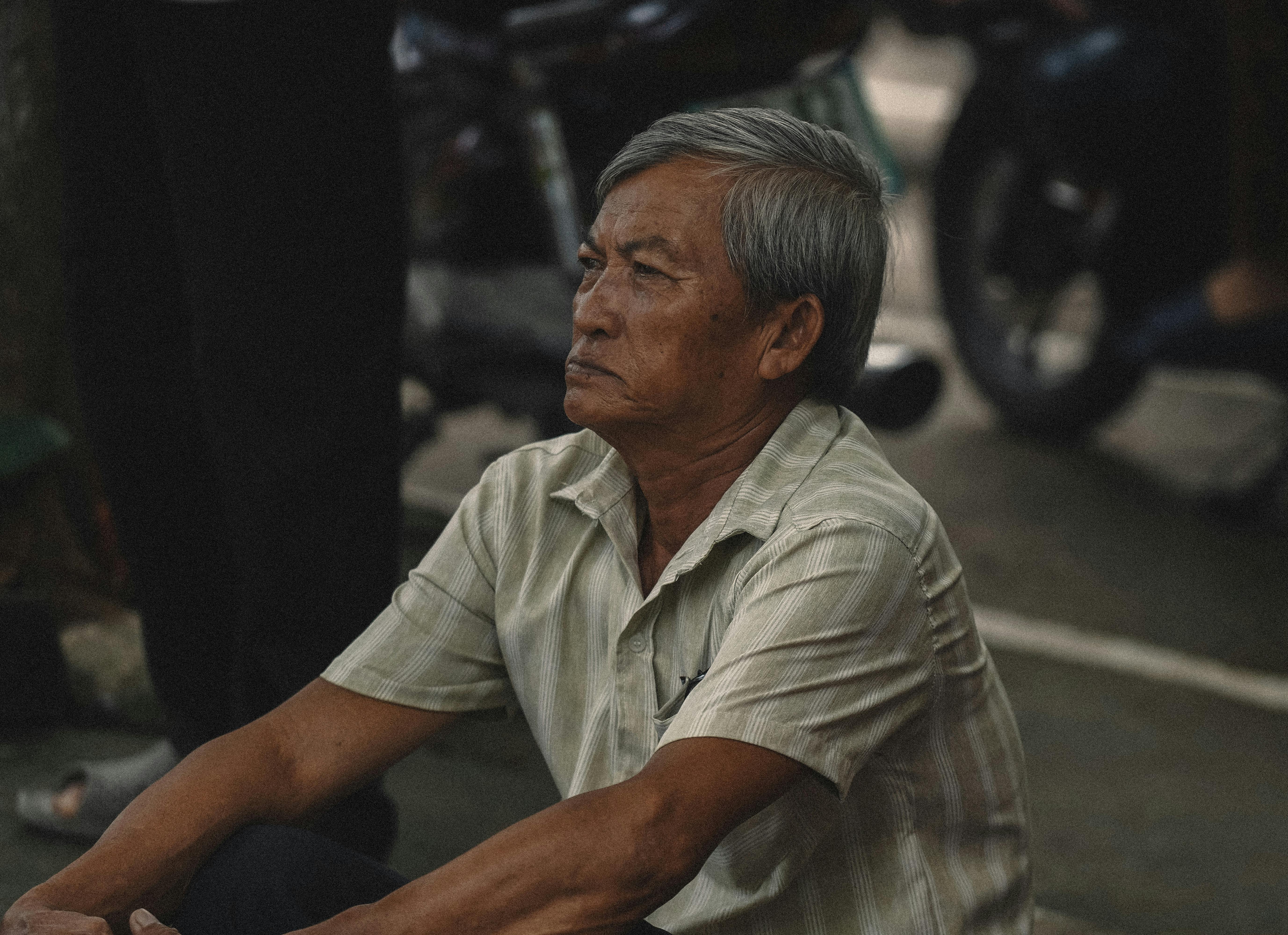 Contemplative elderly man sitting on a street, capturing a moment of peaceful reflection.