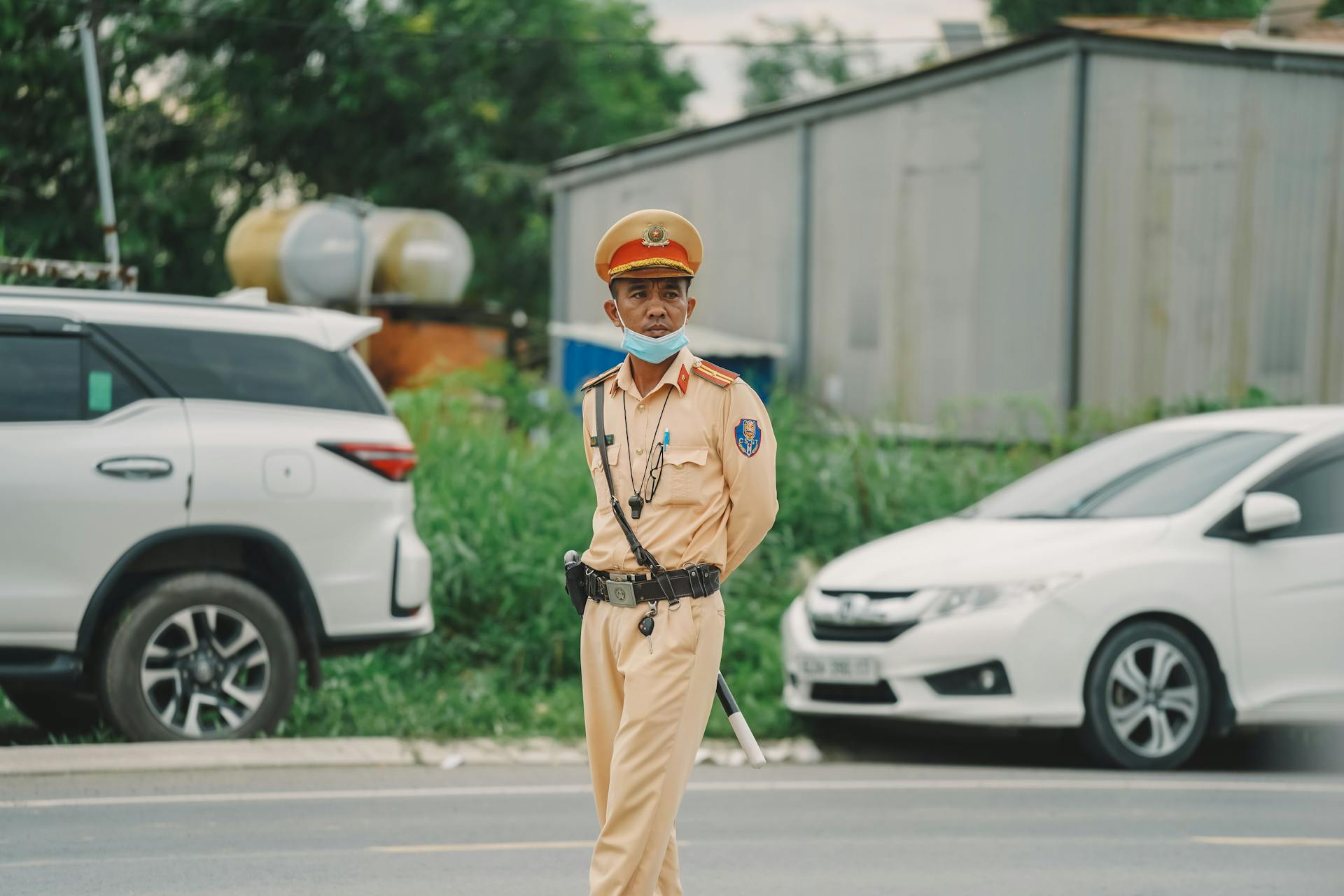 A traffic officer wearing a uniform and mask managing vehicles on a busy urban street.