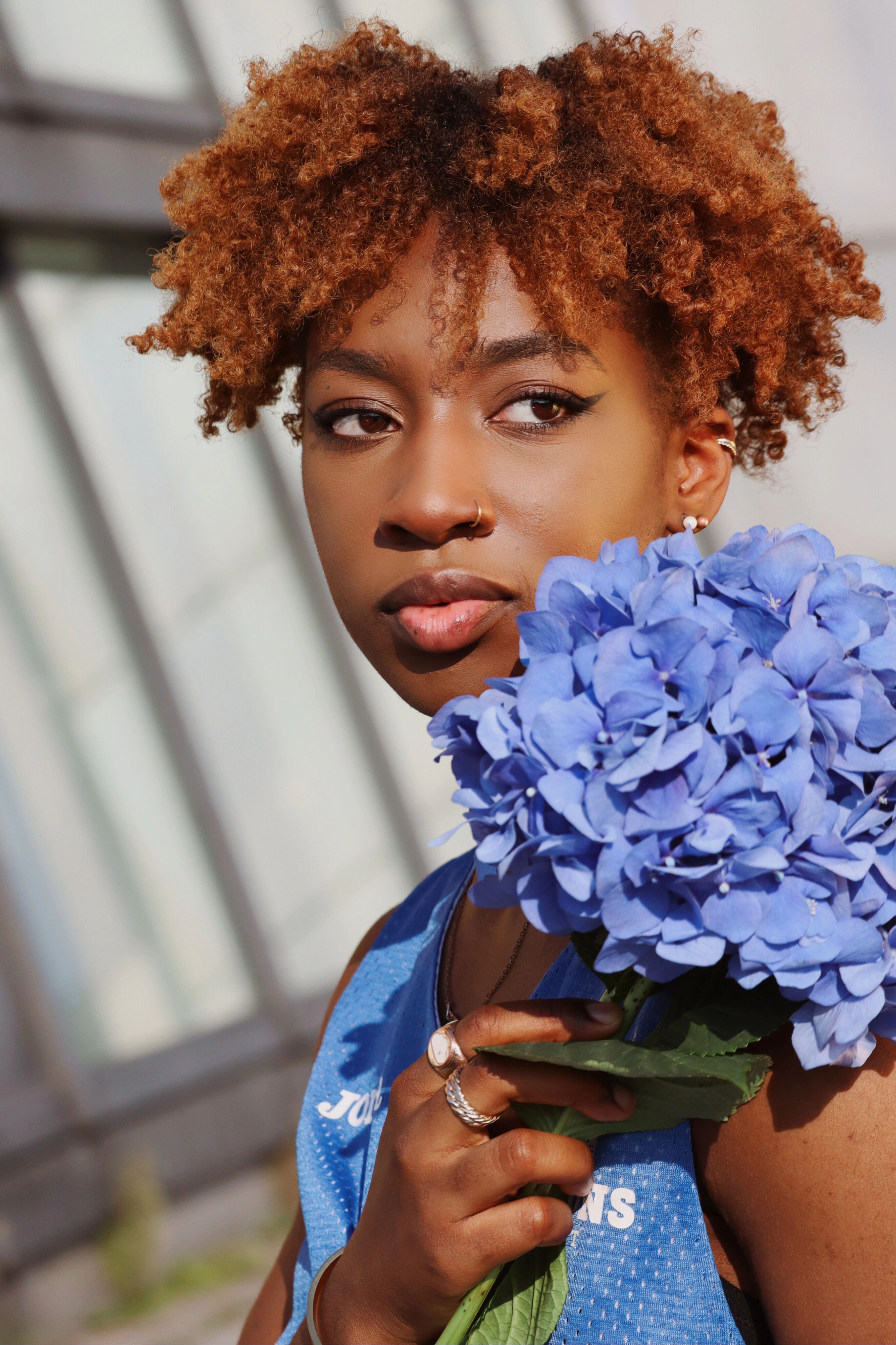Stylish woman holding blue hydrangeas, captured in Berlin outdoors with natural light.