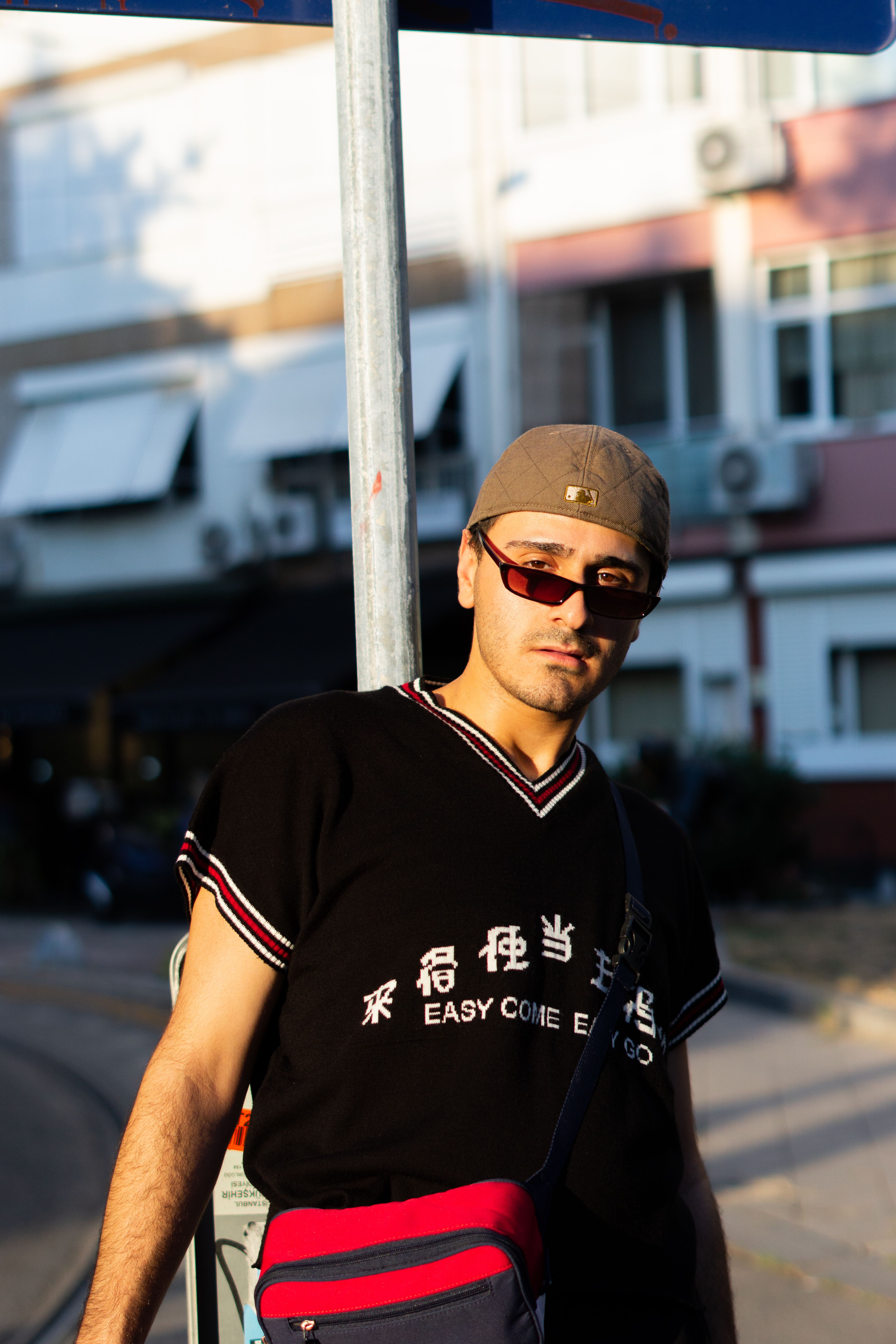 Trendy outdoor urban portrait of a young man wearing sunglasses and a cap on a sunny day.