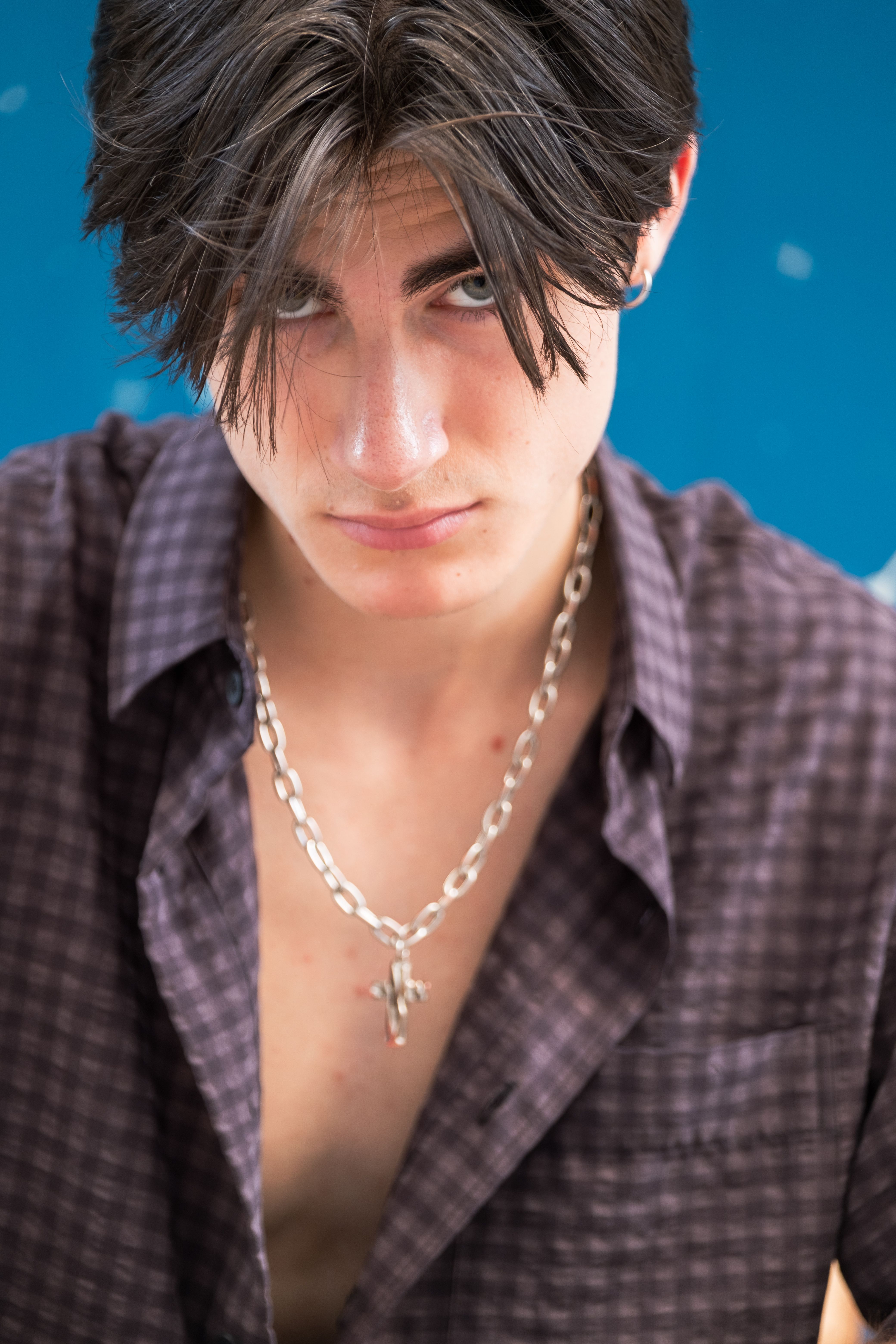 Close-up portrait of a young man with a stylish look and silver chain, exuding confidence and urban fashion vibes.
