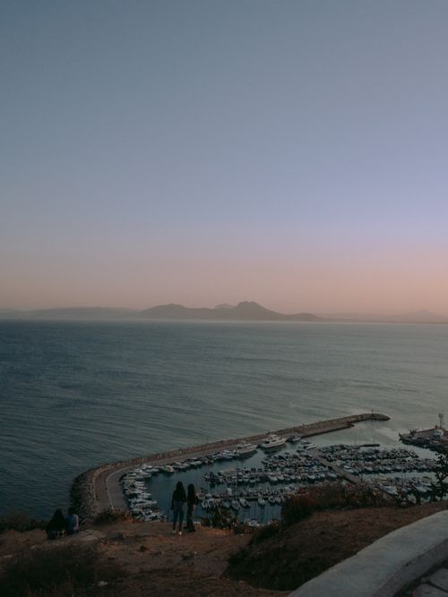 Free A serene view of a marina against a backdrop of mountains at dusk in Tunis, Tunisia. Stock Photo