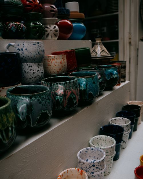 Free Vibrant array of Moroccan ceramic mugs and vases on market shelves in Essaouira. Stock Photo
