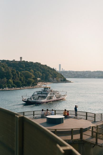 Tourboat sailing through the Bosphorus Strait in Istanbul with people enjoying the view.