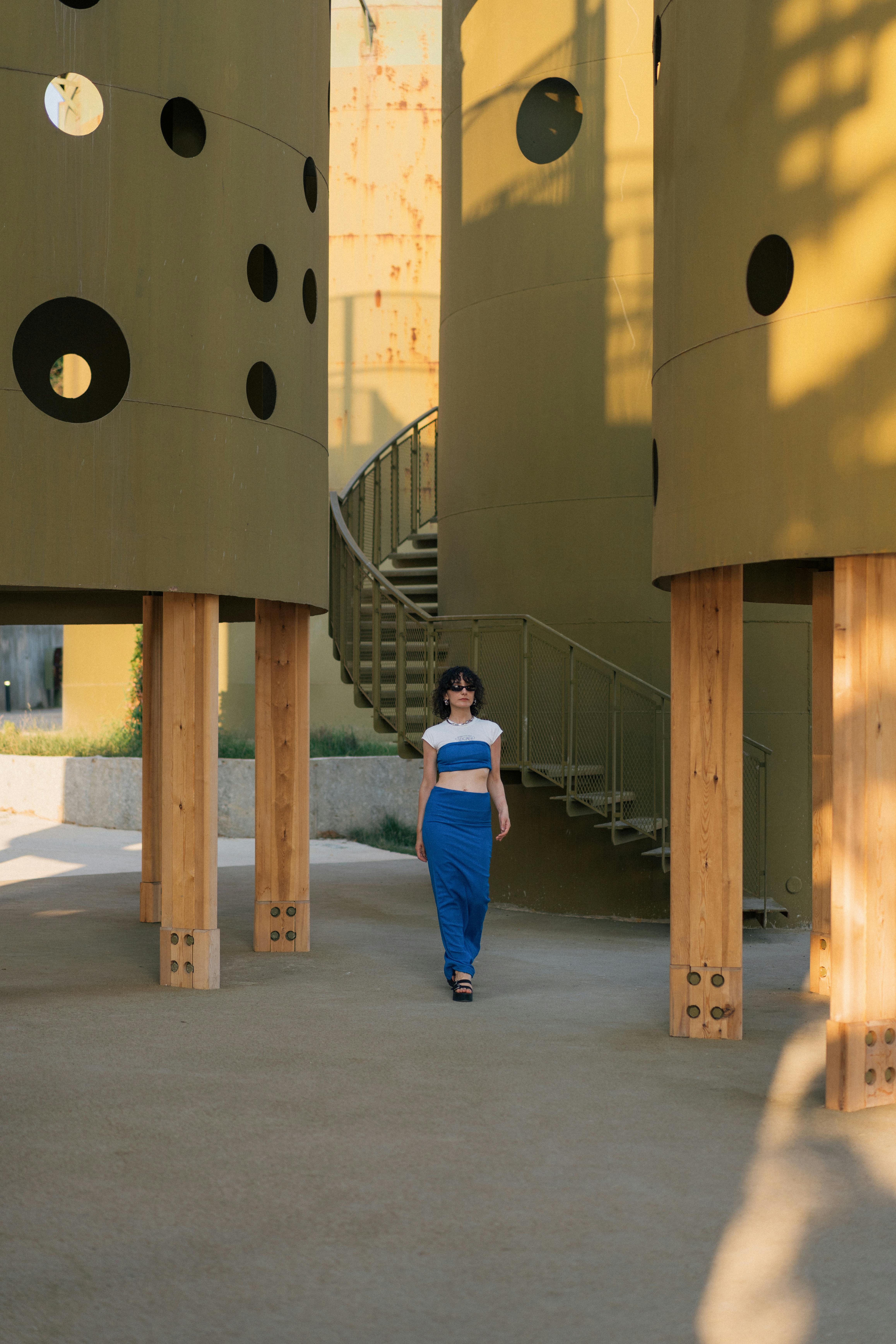 Woman poses confidently in a modern architectural setting with cylindrical structures in vibrant Istanbul.