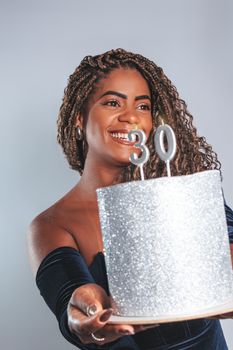 Beautiful woman holding a glittery cake with number 30 candles, celebrating her birthday with joy.