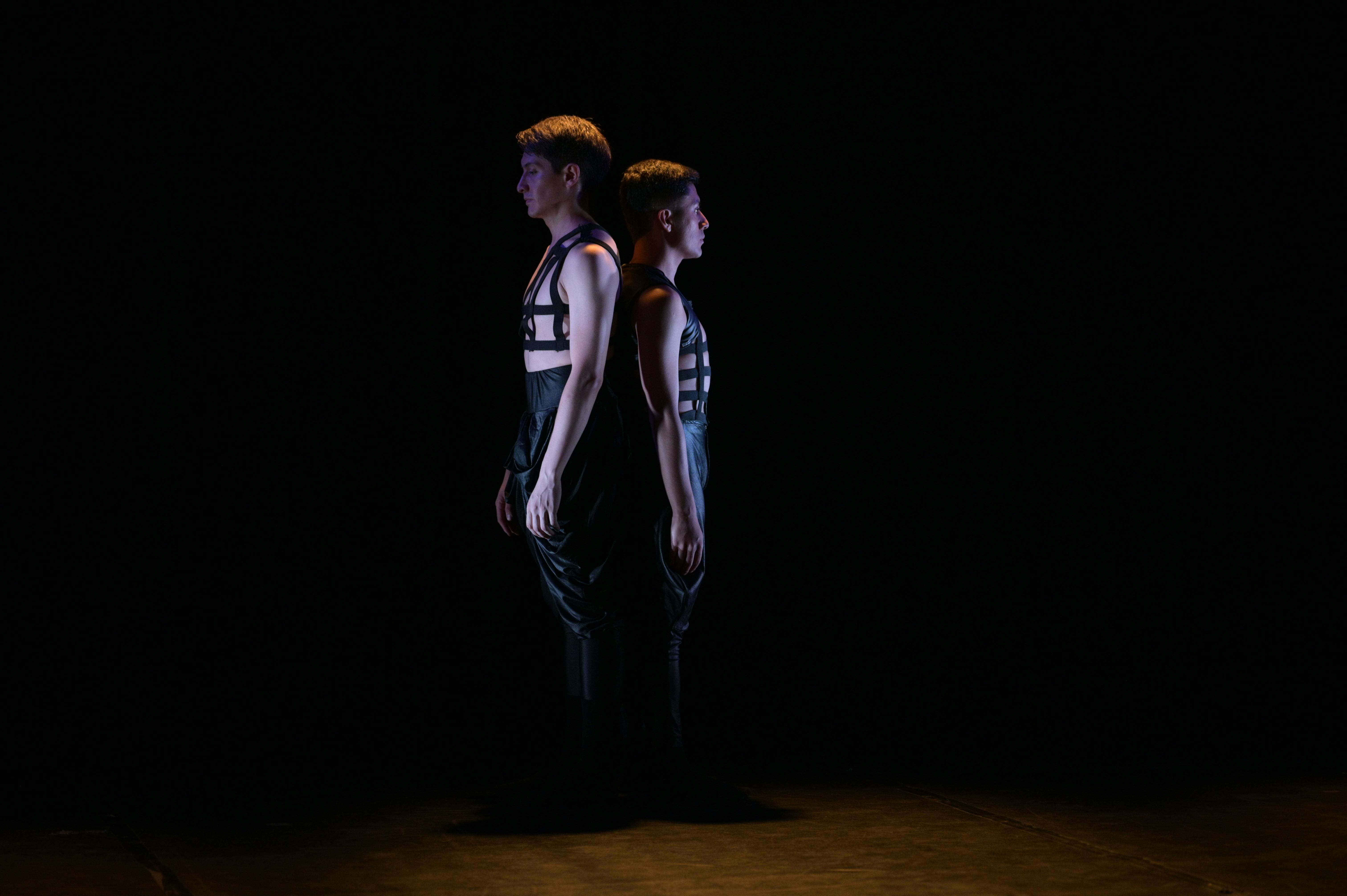 Free Two male dancers in dramatic stage lighting, creating a striking silhouette in a dark studio. Stock Photo