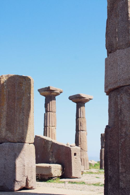 Free Ancient stone columns stand beneath a clear blue sky at a historical site. Stock Photo
