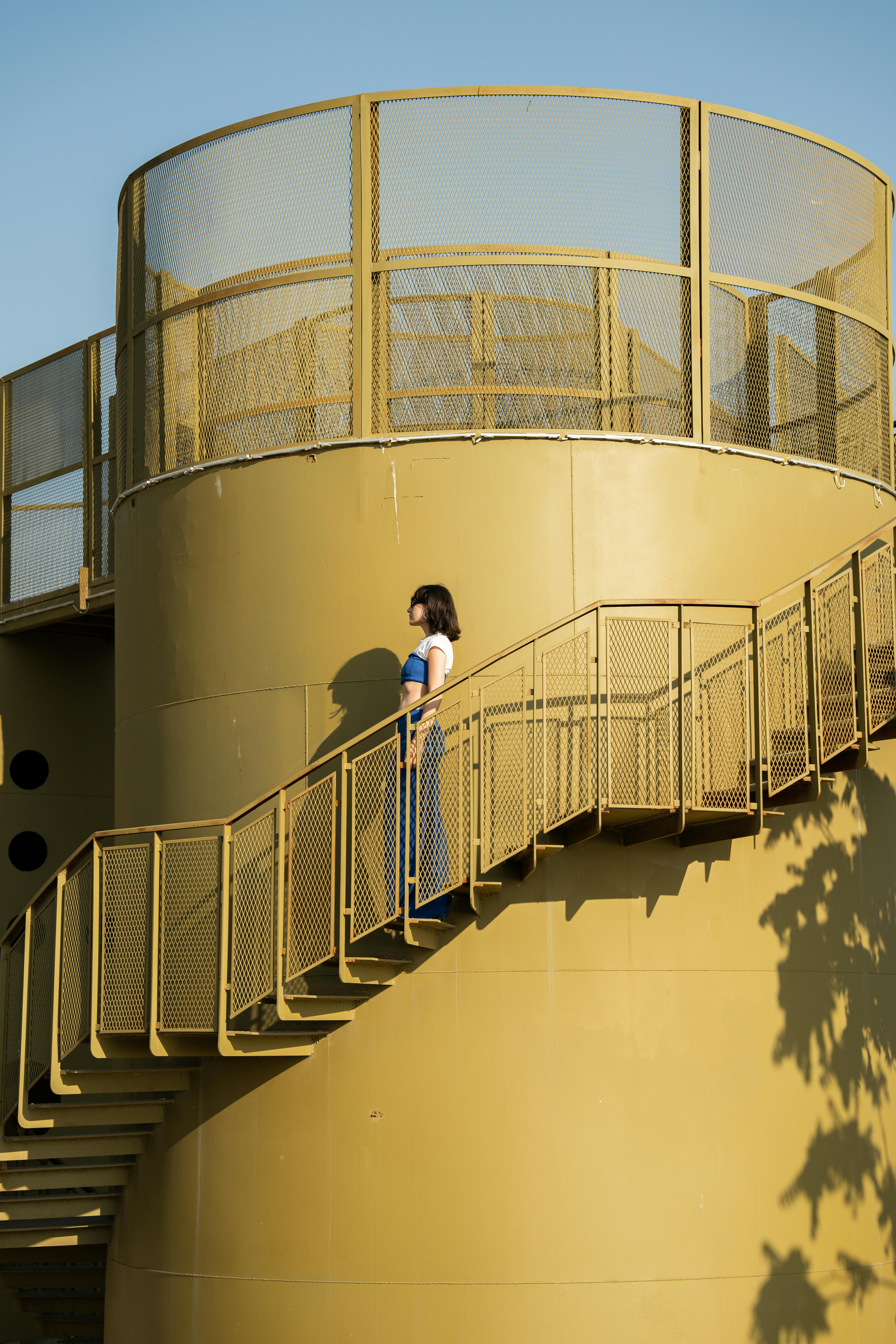 A woman ascends a sunlit modern staircase in İstanbul, Türkiye.