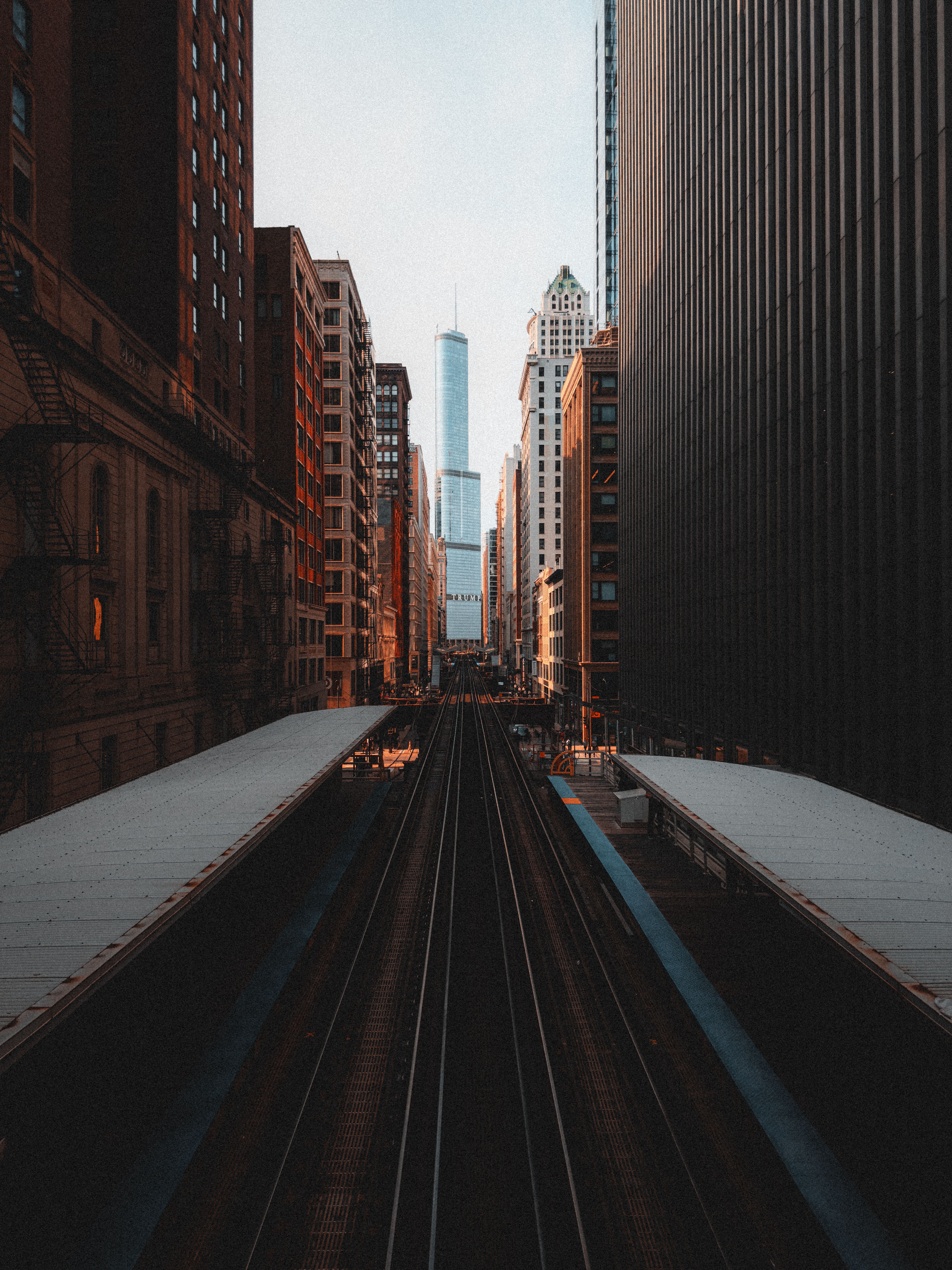 A dramatic perspective of urban skyscrapers and railway tracks in downtown Chicago at dusk.