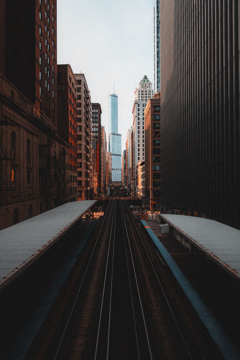A dramatic perspective of urban skyscrapers and railway tracks in downtown Chicago at dusk.
