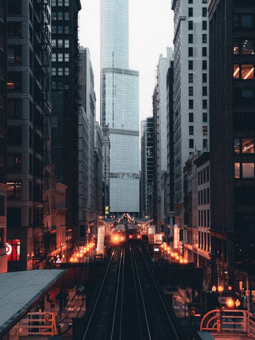 Free Evening view of urban railway lines surrounded by skyscrapers with illuminated lights in a bustling cityscape. Stock Photo
