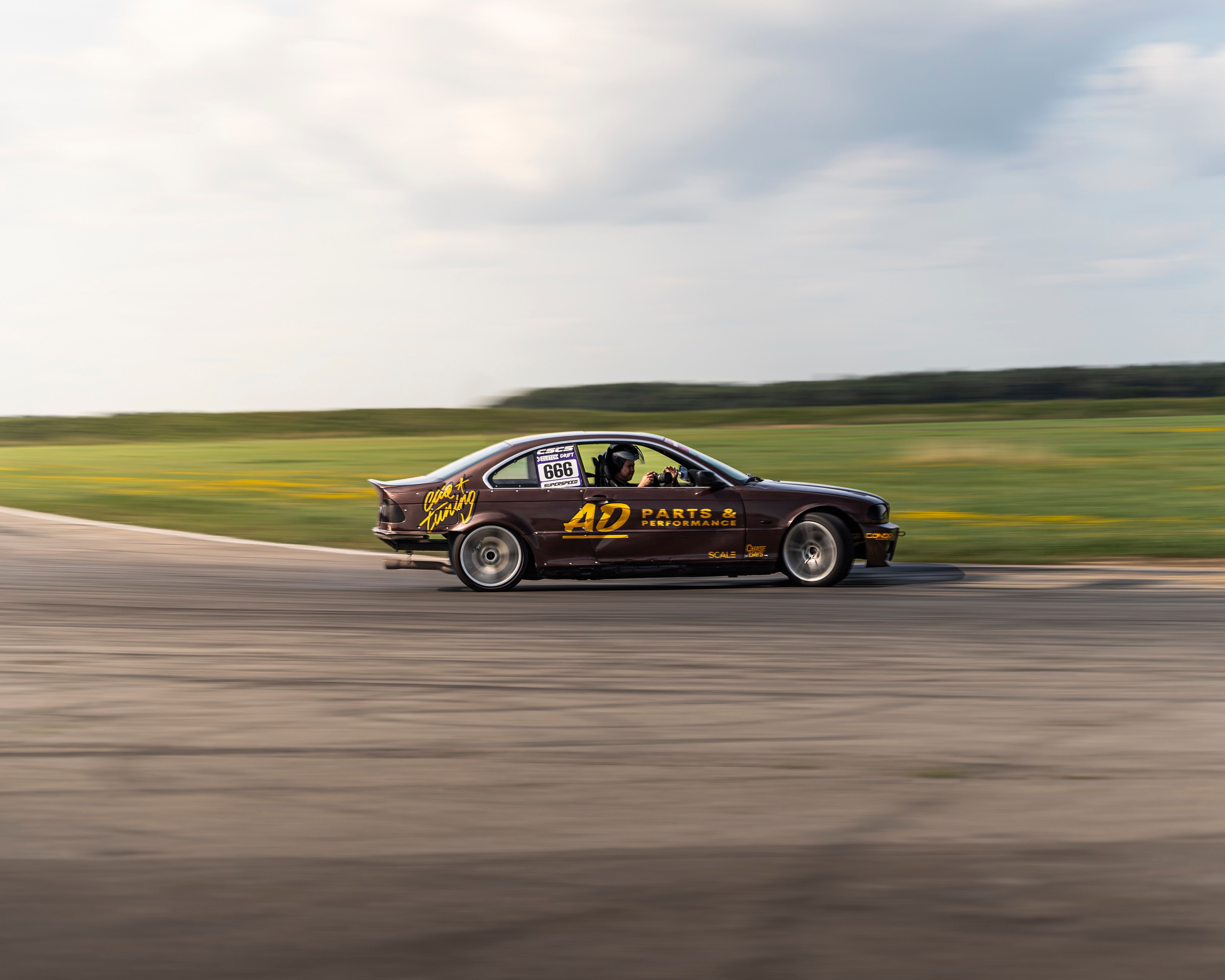 A sleek car drifting swiftly on a racetrack, showcasing speed and precision in an outdoor setting.