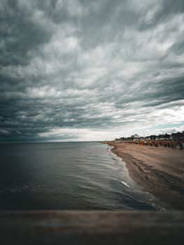 An overcast sky looms over the sandy shore of Dahme Beach in Germany with the calm sea in view.