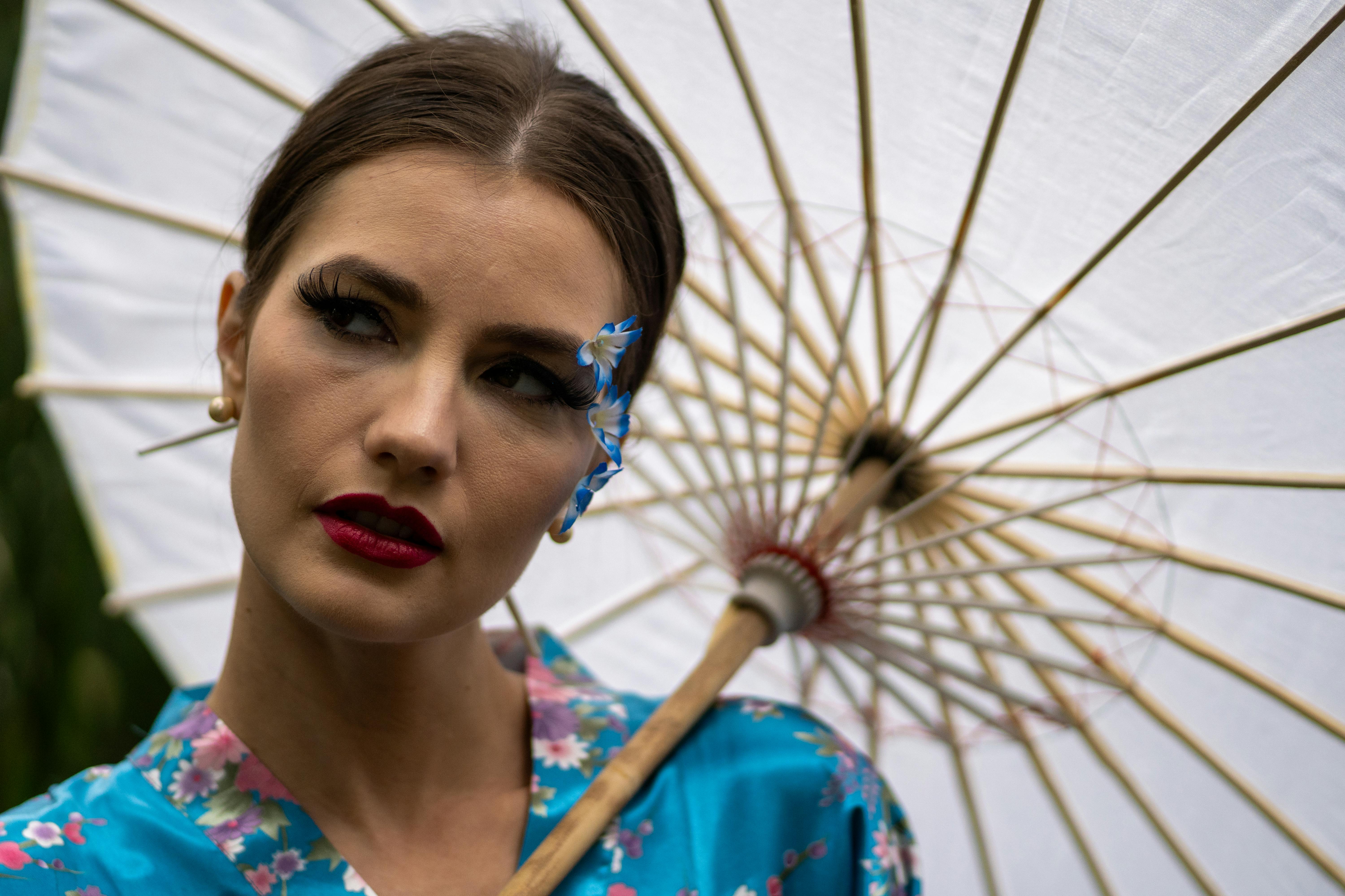 a woman in a blue kimono holding an umbrella