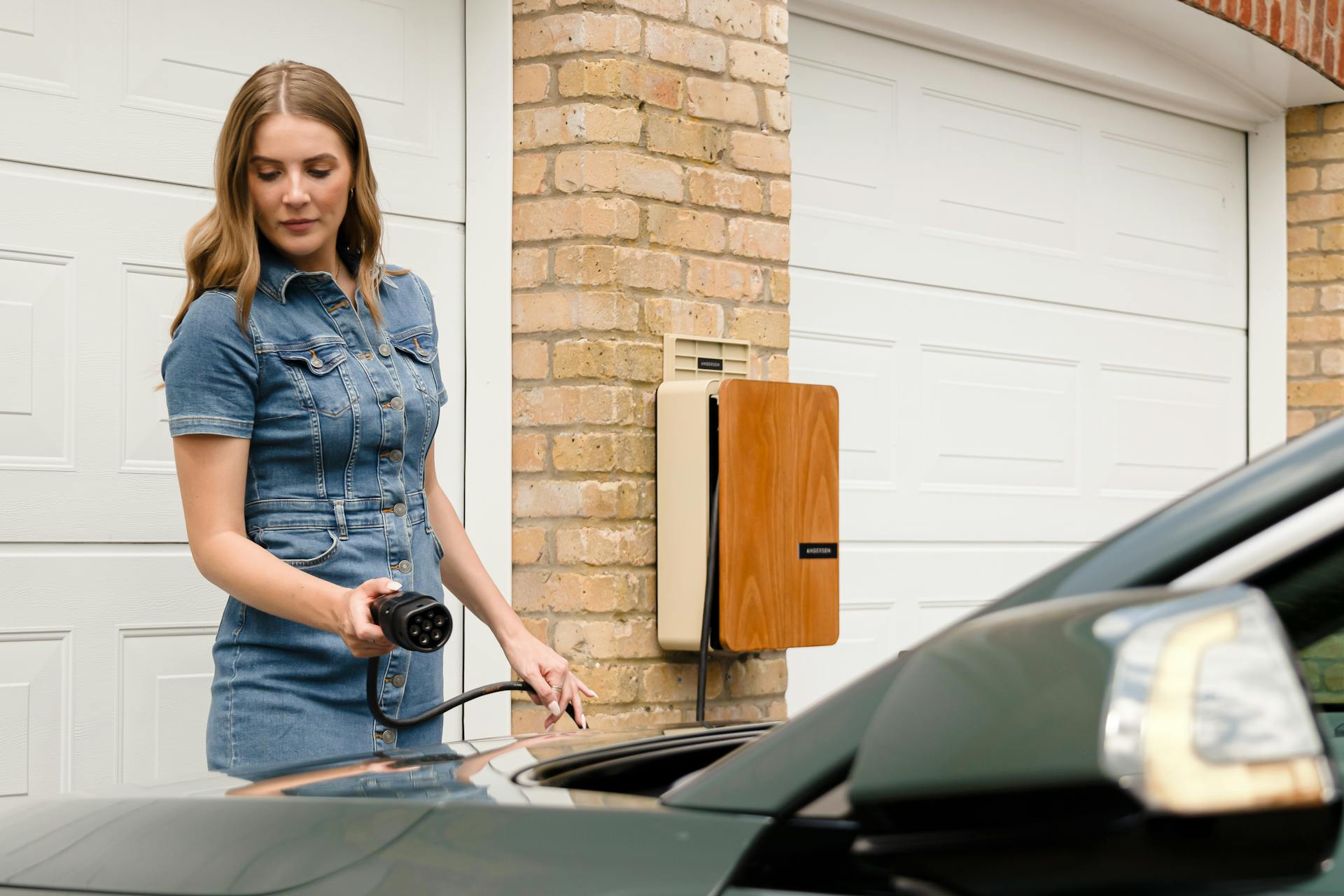 Young woman using an Andersen domestic EV charge point to charge a fully electric Kia Niro EV at home