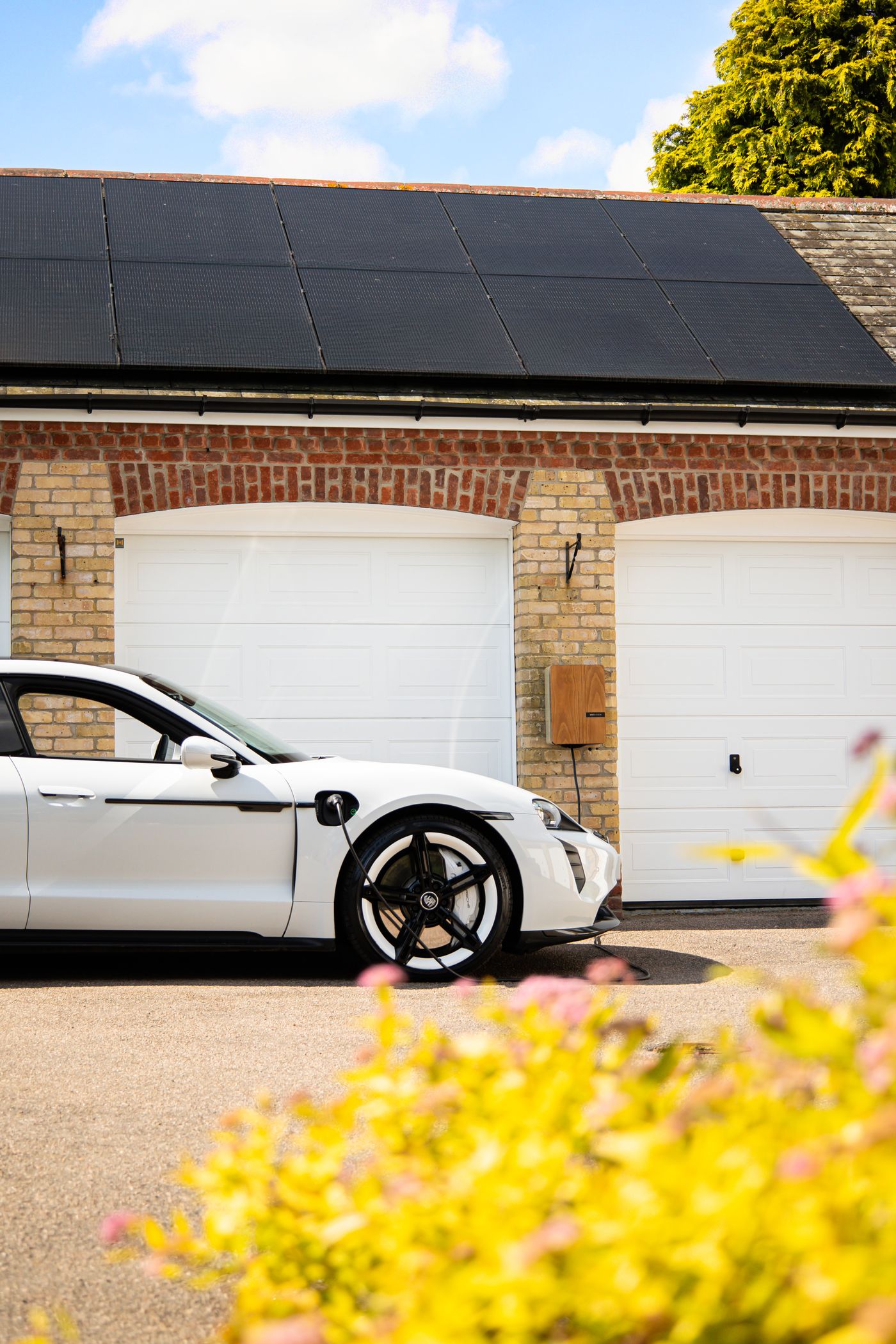 Real stock photo of an electric car charging at a home driveway