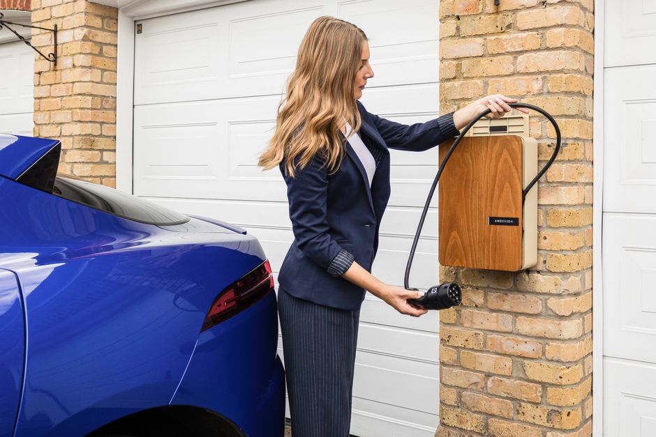 EV charger installation in home garage - home electrician services Woman connecting electric vehicle charger to a blue car in a residential garage, showcasing modern home automation and electric vehicle charging solutions.