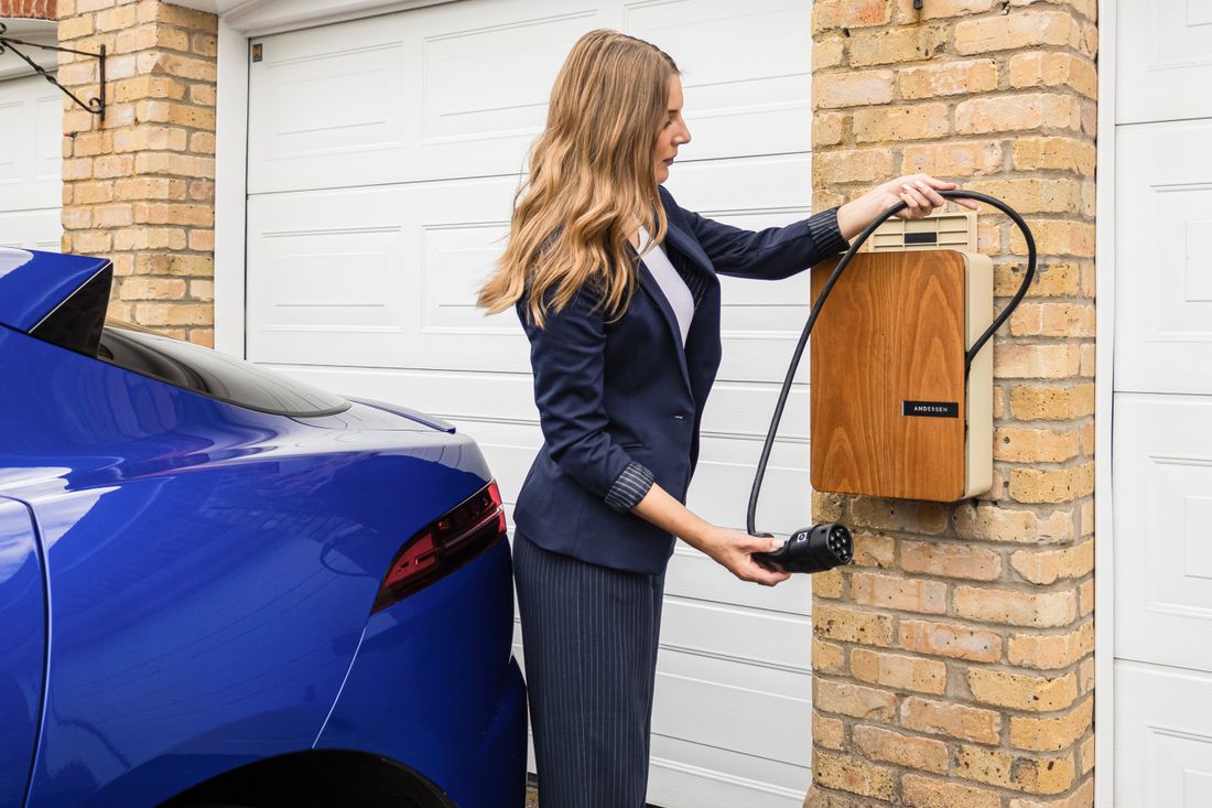 A woman uses a home charging station to charge her electric car