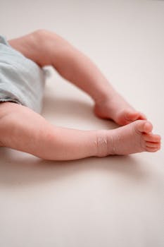 Adorable close-up of a newborn baby's legs and feet lying on a soft surface.