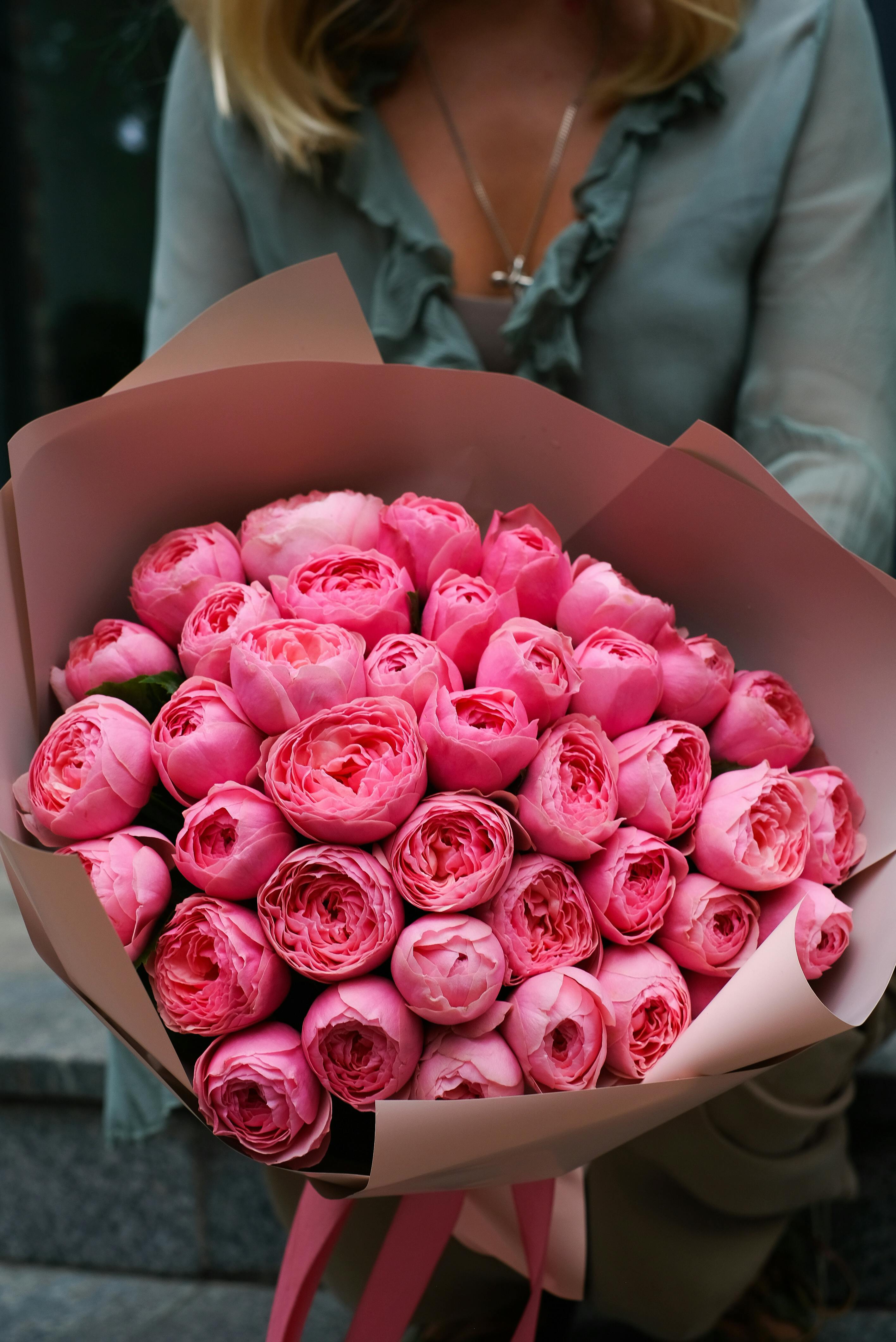 Luxurious bouquet of pink roses held by a woman, perfect for weddings or romantic gifts.