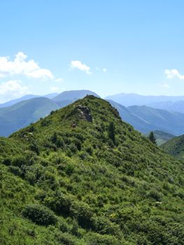 Vibrant summer landscape with lush green mountains under a clear blue sky.