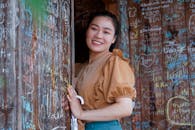 一位开朗的女性站在充满活力的涂鸦墙边，散发着时尚与温暖