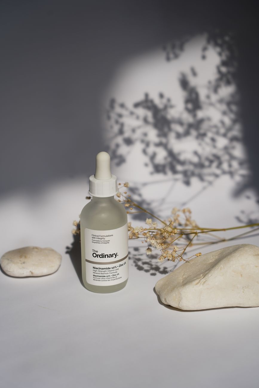 A minimalist still life of skincare bottle with natural shadows and stones, ideal for beauty and wellness themes.