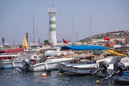 Free A vibrant harbor scene in Foça, İzmir, Türkiye, showcasing boats and a lighthouse on a sunny day. Stock Photo
