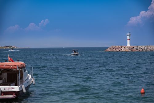 Free Tranquil scene of boats near a lighthouse in Foça, İzmir, Türkiye on a sunny day. Stock Photo