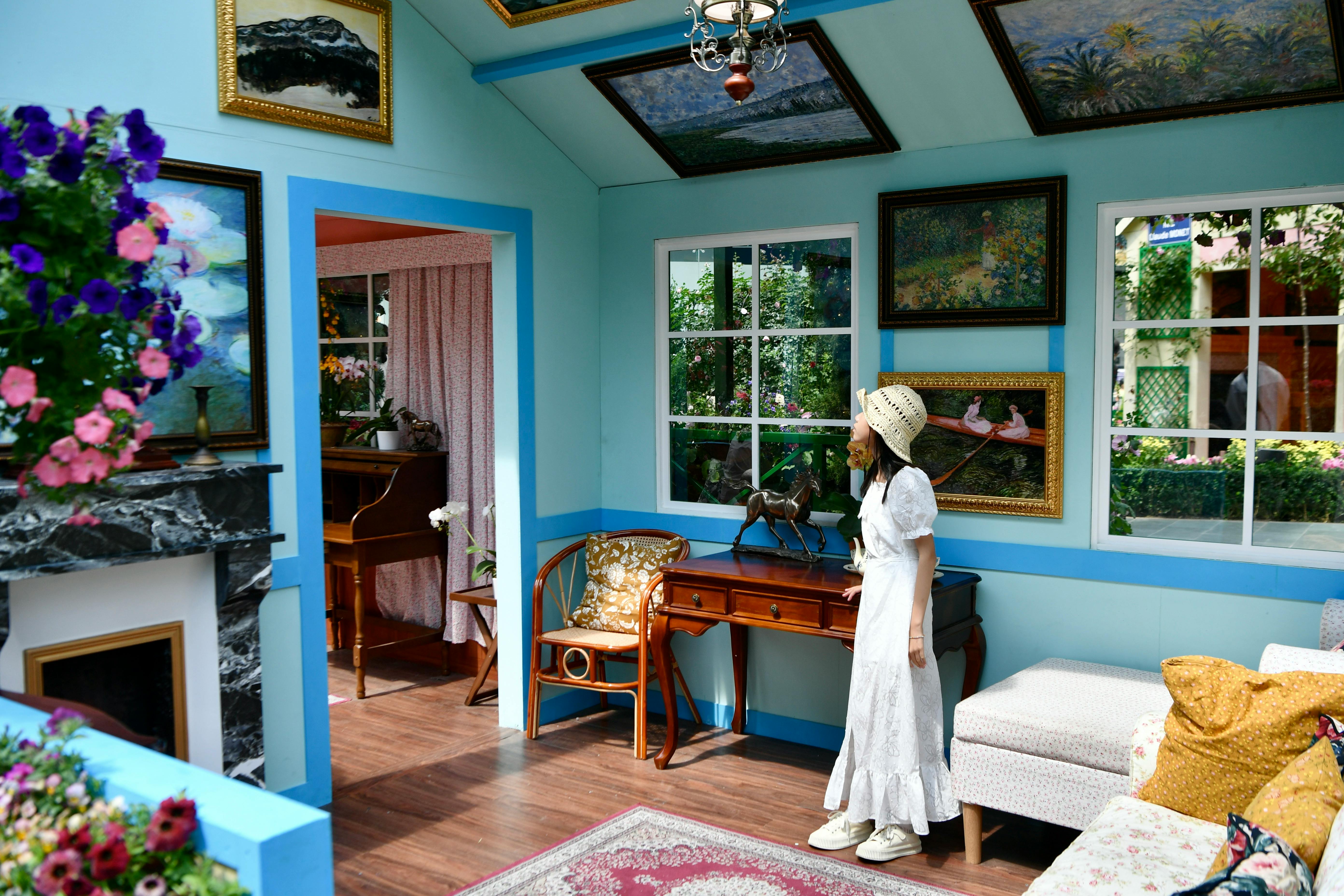 a woman standing in a room with a painting on the wall