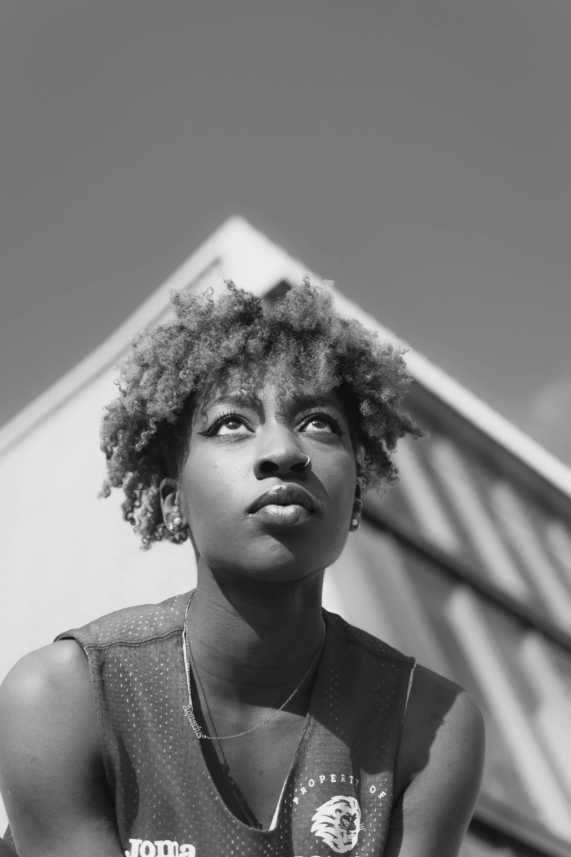 Dynamic black and white portrait of a young woman outdoors with a thoughtful expression.