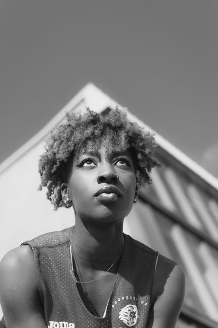 Dynamic black and white portrait of a young woman outdoors with a thoughtful expression.