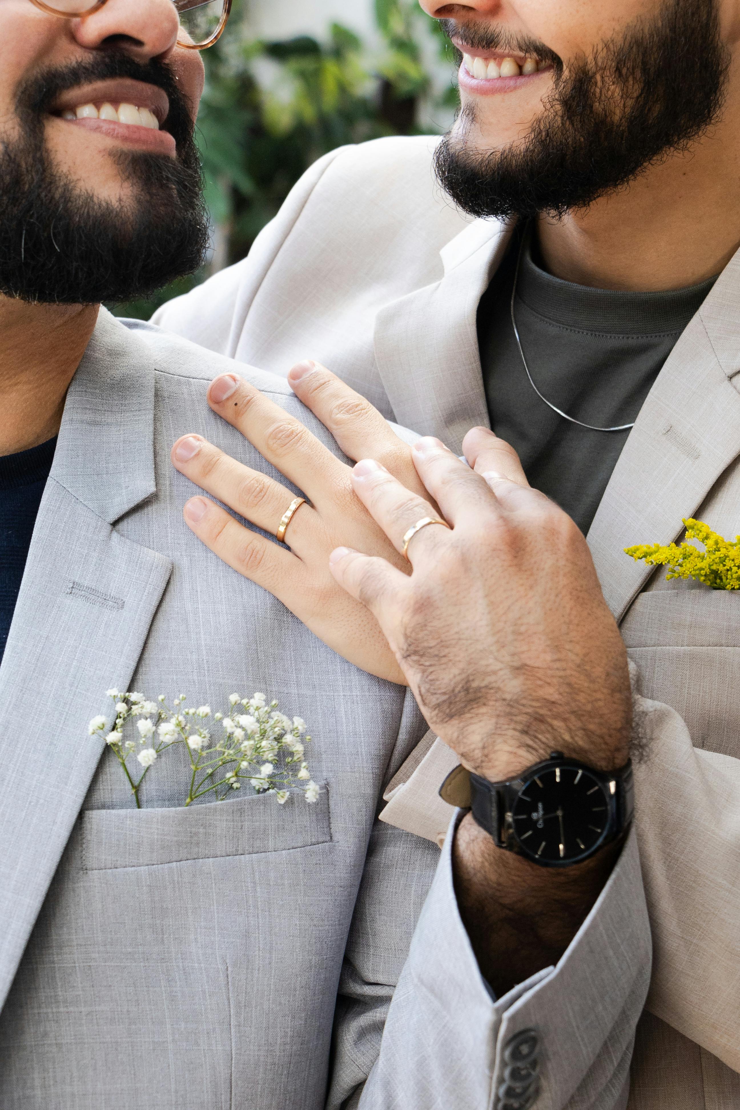 close up of gay couple smiling and showing wedding rings