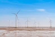 在明亮的蓝天下，广阔的配备涡轮机的风电场展示了可再生能源