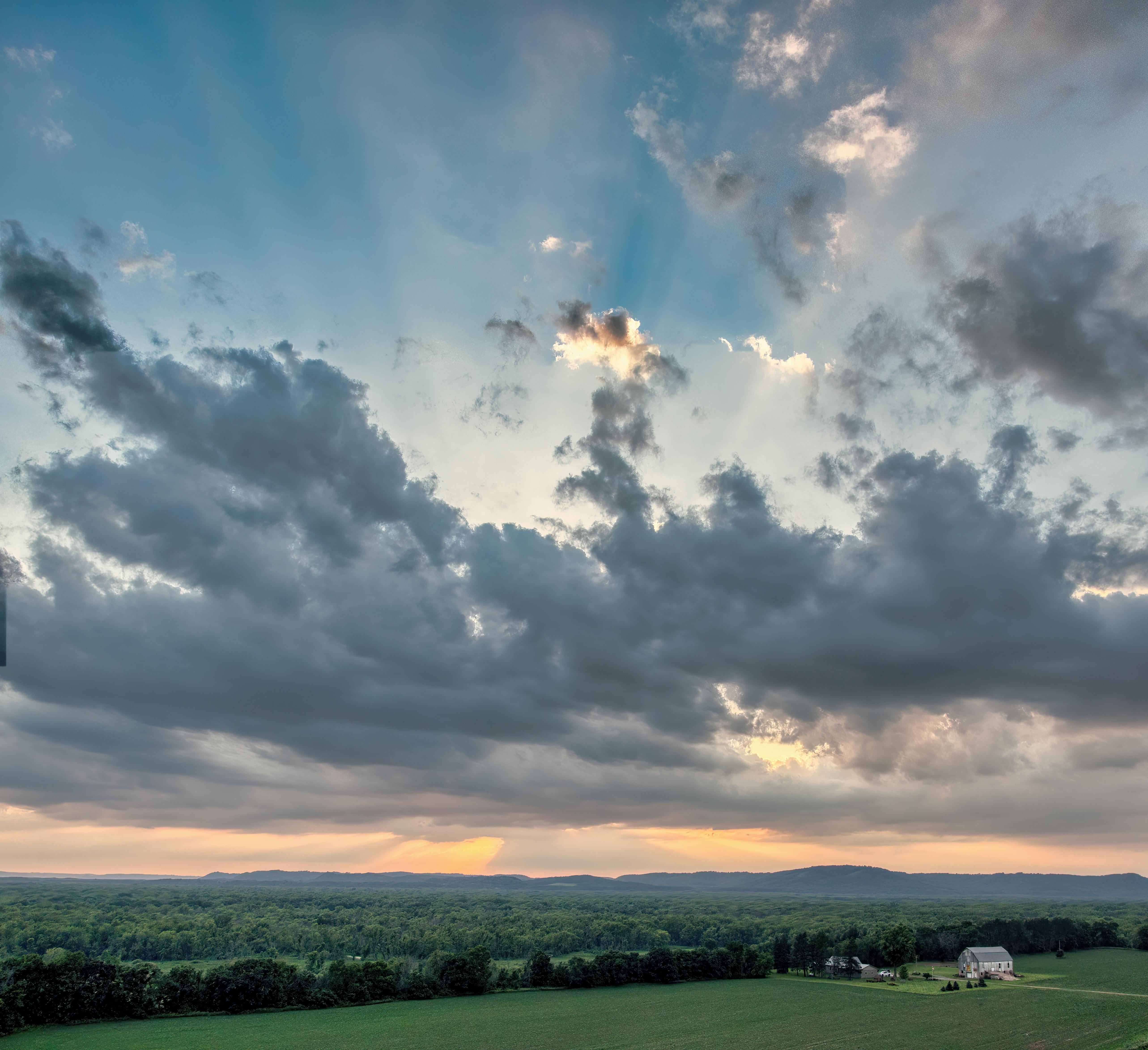 a beautiful sunset over a farm with clouds