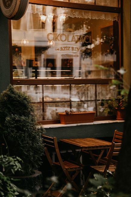 Charming outdoor café setting with wooden furniture and lush plants, offering a warm and inviting atmosphere.